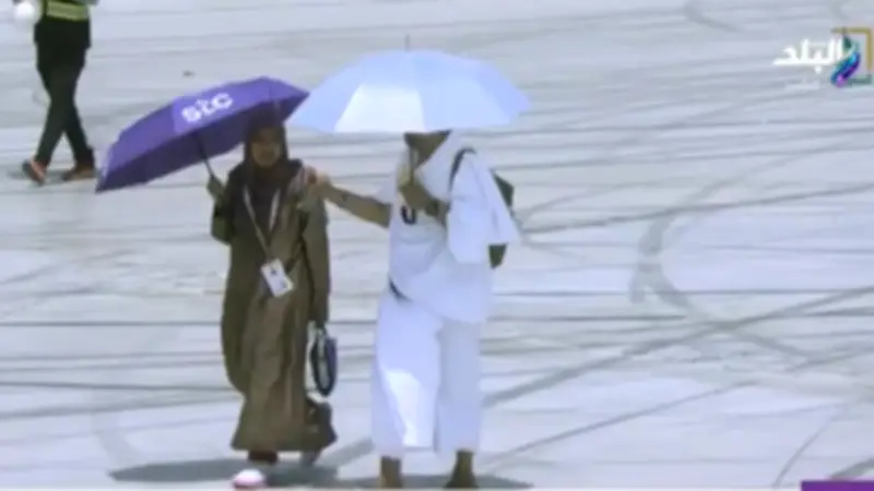 زوج يرش المياه على وجه زوجته لتخفيف حر الشمس في عرفات