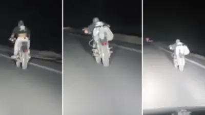 شاب يستلقي على دراجة نارية بطريقة استعراضية على طريق سريع بالوادي الجديد